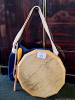 Full view of the handmade drum with the beaded drumstick resting against it.