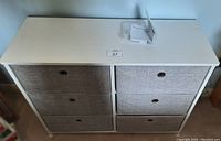 Front view of white frame dresser with four gray fabric drawers and metal ring pulls