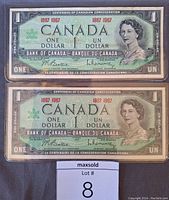 Two Canadian Centennial one dollar bills stacked, showing front side with Queen Elizabeth II portrait and bilingual denomination text.