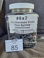 Clear photo of the large plastic jar with over 400 stainless steel deck screws labeled '410 Stainless Steel Deck Screws painted heads', showing the quantity and origin made in Canada by H. Paulin & Co.
