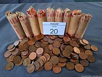 Photo of the lot showing over 700 loose pennies spread in front of ten wrapped paper rolls, each labeled for 50 pennies.