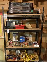 Overall view of shelving with space heater on top, assorted tools and hardware on lower shelves
