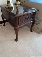Front view of one side table showing drawer and carved legs