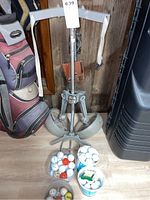 Full view of the Spartan golf caddy folded up with four containers of mixed golf balls placed below it on floor