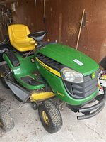 Front left side view of John Deere D120 riding mower showing body, cutting deck and front bumper