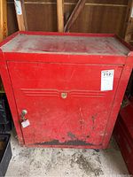 Full front view of red metal locking tool cabinet showing size, color, and overall condition including rust and wear.