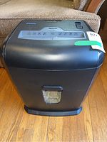 Front view of black Staples paper shredder showing the transparent shred bin window containing shredded paper.