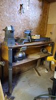 Full view of lathe mounted on wood tabletop with metal legs, motor shelf, power strip, and clamp box visible.