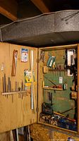 Wide view showing a wooden cabinet containing various hand and power tools including Bosch PST 50-E jigsaw, screwdrivers, drill bits, and files.