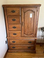 Front view of the wooden wardrobe with five small drawers on left, two larger drawers at bottom, and a closed door cabinet on right.