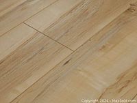 Close-up image of the vinyl plank showing light wood grain and natural wood pattern in beige tones.