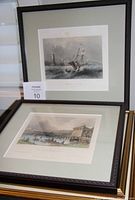 Full view of two framed prints placed leaning against a wall, each with green matting and brown wooden frames.