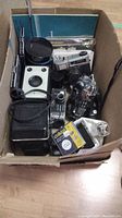 Overall assortment of cameras and accessories in cardboard box