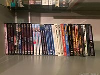 Shelf with DVDs including Curb Your Enthusiasm seasons one and three, Looney Tunes, Stand is Born, High School Musical, and The Last of the Mohicans.