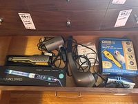 Drawer shot showing all items in the lot including curling iron box, flat iron, blow dryer, massager, and pet clipper box.