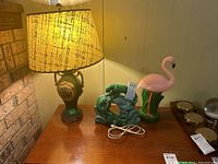 Photo showing all three items on table: ceramic lamp with shade, green panther lamp, and pink flamingo blow mold lamp.