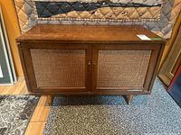 Front view of mid-century media cabinet showing cane front doors and wood finish