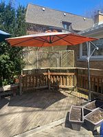 Full view of cantilever umbrella installed on wooden deck, showing orange canopy and metal frame.
