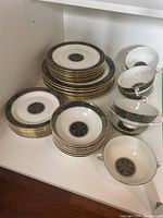 Full set view showing stacks of dinner plates, bowls, and bouillon cups on a white shelf