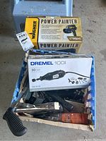 Photo of Wagner Power Painter and Dremel 100 tool boxes on top of milk crate filled with hand tools including stapler and other hand tools.