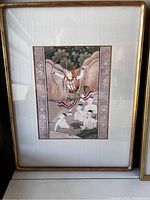 Antique Thai framed artwork showing a figure on a swing with three other figures below, all dressed in traditional Thai attire, surrounded by a decorative floral mat and set in a golden frame.