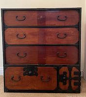 Front view of the Japanese Tansu cabinet dresser showing four drawers with traditional black metal hardware and decorative corner guards.