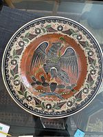 Top view of large ceramic display plate with black bird design and decorative border