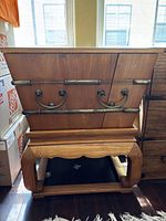 Front and side view of wooden chest on stand showing metal trim and drop handles