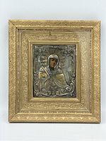Front view of gilt wooden frame with embossed metal relief depicting saint