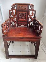 Full front view of carved wooden chair showing seat, arms and backrest