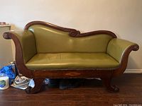 Full view of antique settee with green leather and carved wooden frame