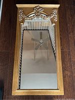 Full view of the gold gilt framed vertical mirror showing overall shape, mirror glass, and reflective surface.
