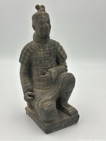 Front left diagonal view of the kneeling terracotta warrior figurine showing detailed armor plates and facial features