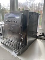 Front-left angle of machine on countertop showing drip tray, portafilter area, steam wand and side venting