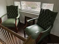 Front angle view of both green leather armchairs near a window