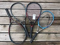 All three tennis rackets laid flat on wooden deck, showing heads and grips.