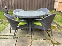 Front view of round resin wicker table and four chairs arranged outdoors