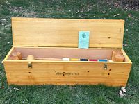 Open wooden box showing empty interior and booklet leaning on lid.