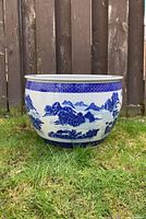 Front centered view of round blue and white porcelain jardiniere showing detailed landscape pattern and wide open rim