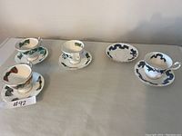 Four different fine china teacups and saucers arranged in a row, showing various patterns and styles.