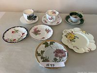 Overview of all teacups, saucers, and decorative plates arranged on a table showing floral patterns and different shapes.