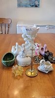 Lot of assorted decorative items including ceramic figurines of swans, squirrels, a girl figure, a green basket bowl, a brass tree, and a white petal-edged pedestal vase.