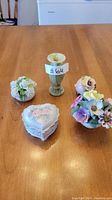 Photo showing all five assorted decorative items on a wooden table including floral decor pieces, a heart-shaped trinket box, and a candle holder with candle.