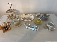Lot of assorted porcelain and china including teacups, saucers, serving trays, and teapot arranged on table.