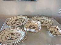 Full view of assorted serving plates and bowls showing floral pattern and textured edges.