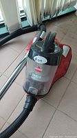 Close-up of Bissell Zing II vacuum canister showing clear dust compartment and hose attachment.