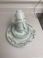 Stacked view of cups, saucers, and plates highlighting floral pattern and overall set composition.