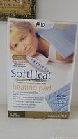 Photo of the SoftHeat heating pad packaging front, showing product branding, features, image of a woman using the pad, and product details.