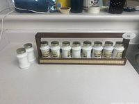 Front view of spice rack holding 10 labeled spice jars plus 2 extra jars to the side.