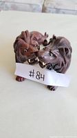 Photo showing pair of wooden lion figurines, close together, with paper #84 in front.